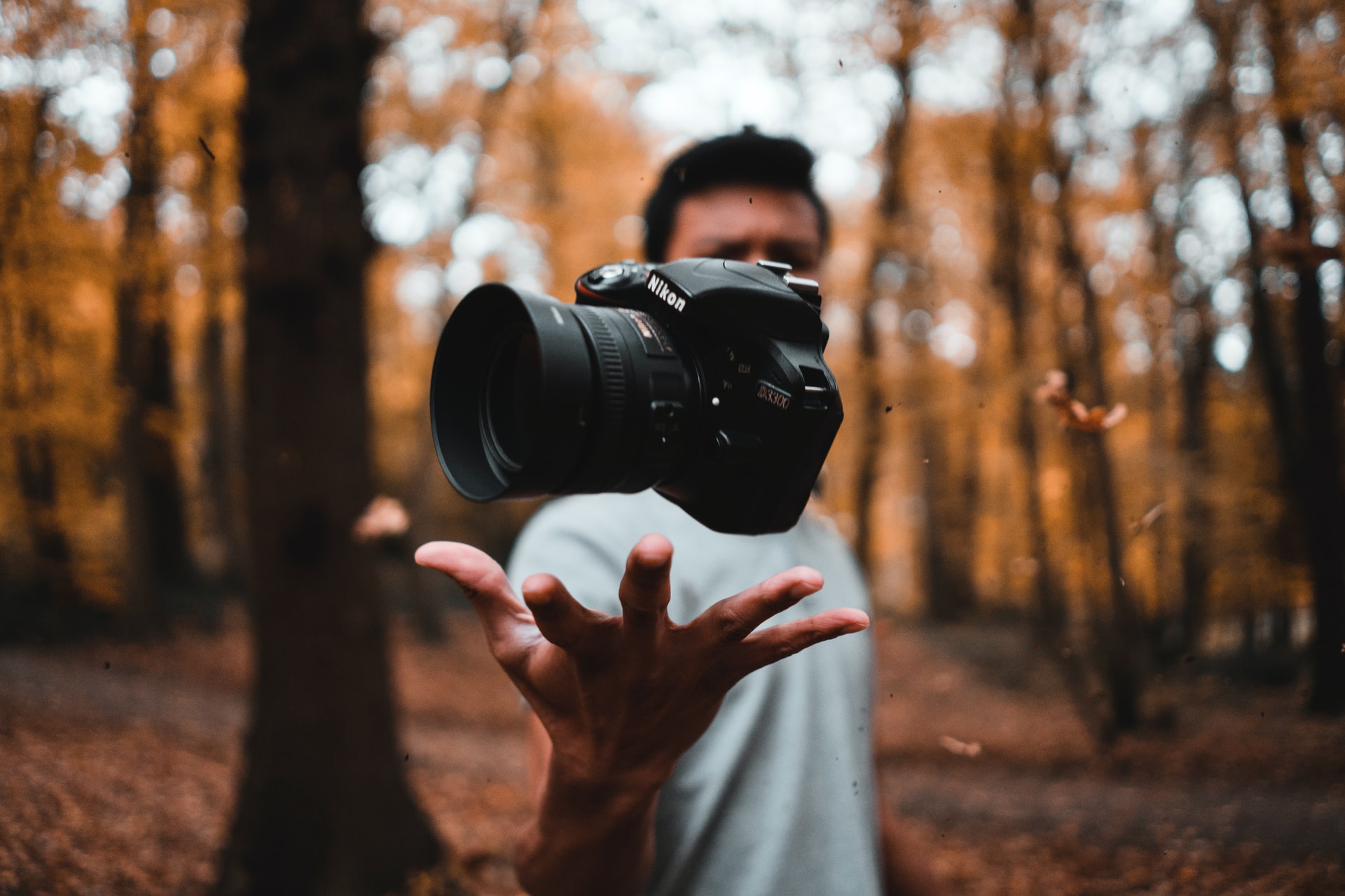 A man gently tossing a camera in the air.