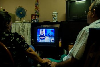 A couple holding hands while watching TV.